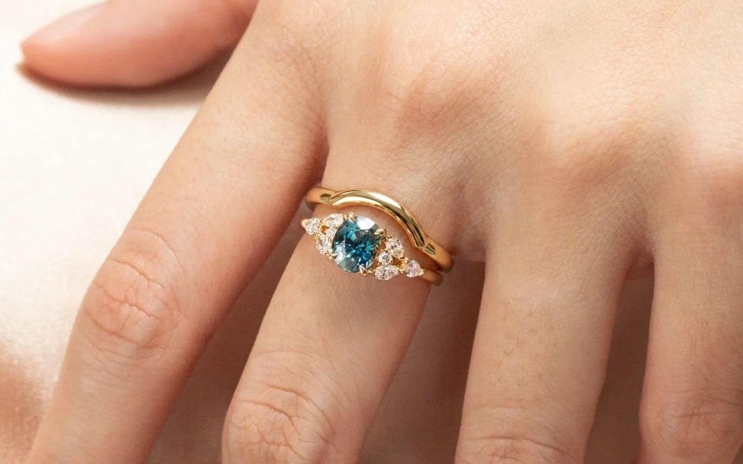 Curved wedding band worn against a sapphire engagement ring — Bonnot Paris